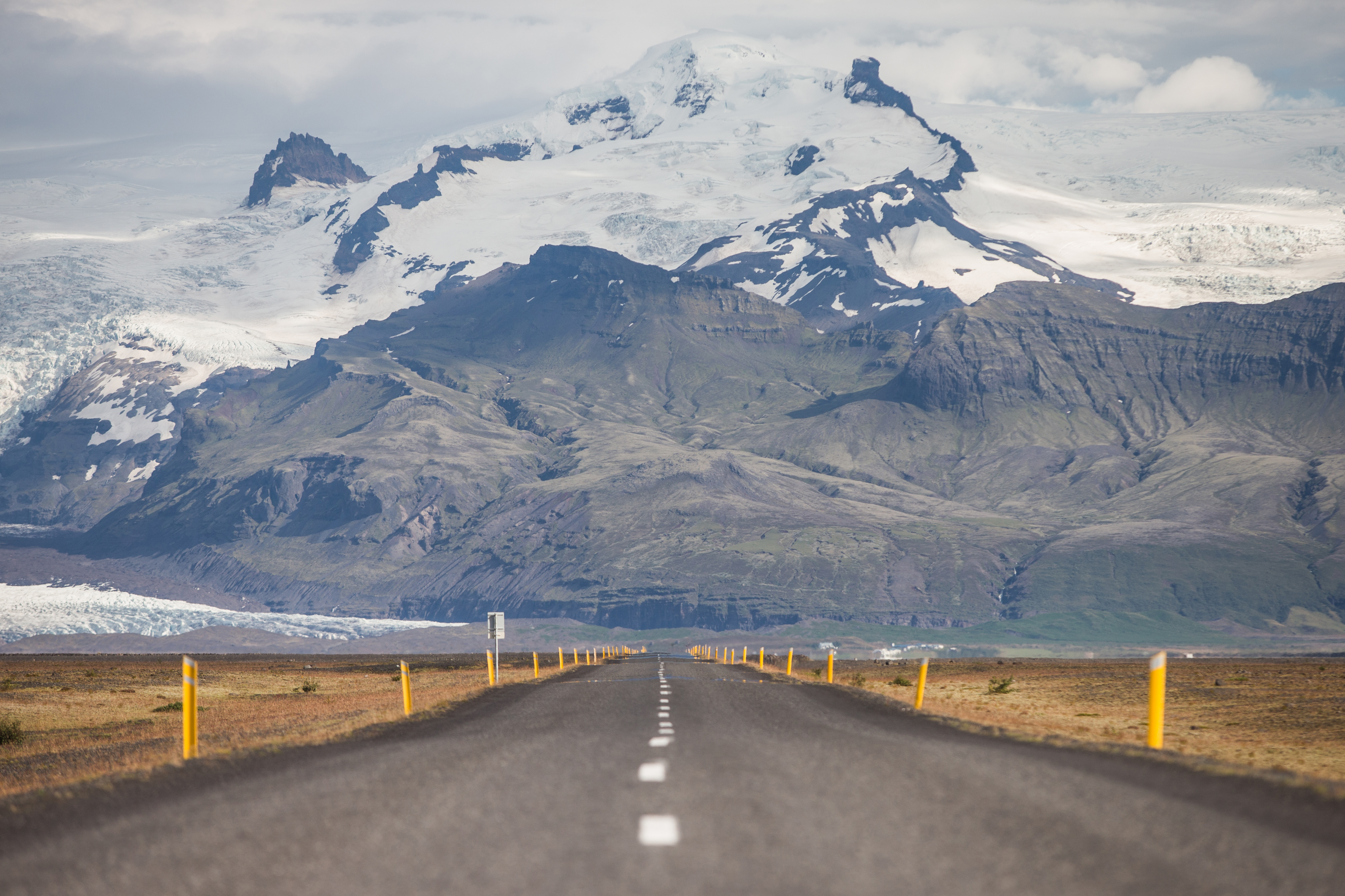 Straight road leading directly toward a massive glacier and mountains